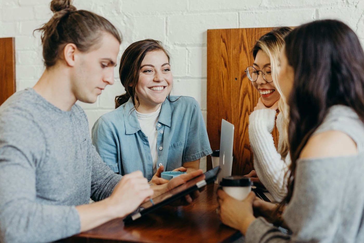 Four friends smiling and talking over coffee