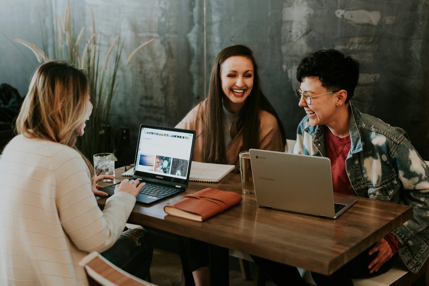 Three people laughing while working on laptops