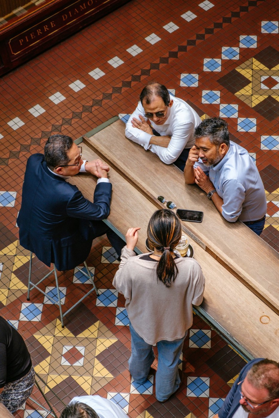 Friends leaning in around a long table, deep in conversation